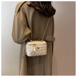 Détail du sac bandoulière en tweed avec logo camélia doré et bandoulière chaîne