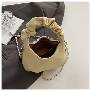 Detail of cream pleated cloud bag showing inner lining, pocket and chain strap texture