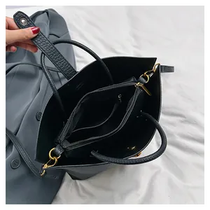 Detailed view of black pebbled leather tote with triple interior compartments and gold hardware