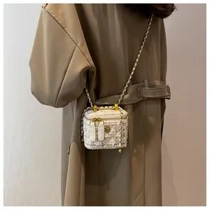 Détail du mini sac bandoulière en tweed avec chaîne dorée porté par un mannequin en manteau