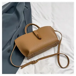 Detail view of brown lychee grain leather tote bag with gold hardware and shoulder strap