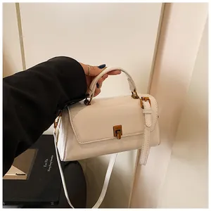 Detail of white patent leather handbag with gold metal clasp and adjustable strap