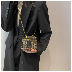 Détail d'un mini sac en tweed avec ornement fleur dorée et bandoulière chaîne