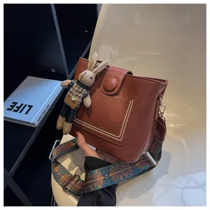 Détail du sac seau marron texture litchi avec bandoulière ethnique et breloque lapin
