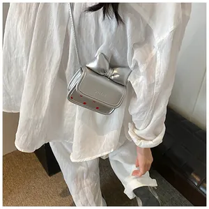 Gros plan d'un mini sac à bandoulière argenté avec nœud papillon et motifs à pois rouges