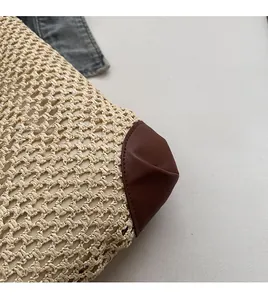 Macro detail of handwoven straw tote bag featuring reinforced brown leather corner stitching