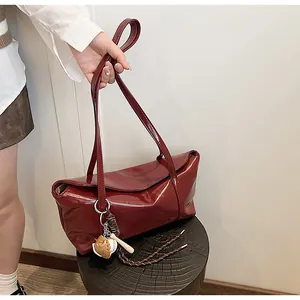 Detailed macro view of glossy burgundy leather bag with a mini baseball pendant ornament