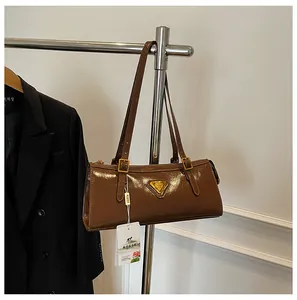 Detail einer dunkelbraunen Lackledertasche mit Metalldreieck und goldener Hardware