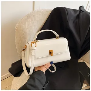 Close-up of white minimalist square handbag with gold hardware and smooth leather finish