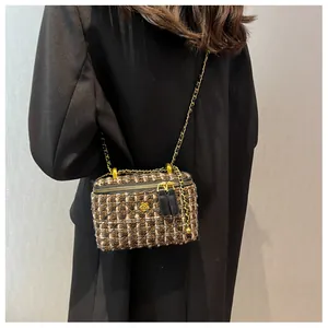 Détail d'un sac bandoulière en tweed avec chaîne dorée et ornement fleur en métal