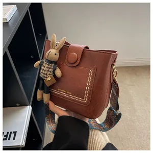 Gros plan d'un sac seau marron avec rivets dorés et breloque poupée lapin décorative