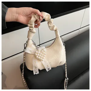 Detail of cream pleated cloud bag featuring lace bow and pearl heart charm accessory