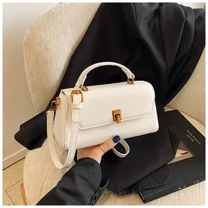 Close-up of white patent leather handbag with golden cylindrical twist lock on a chair
