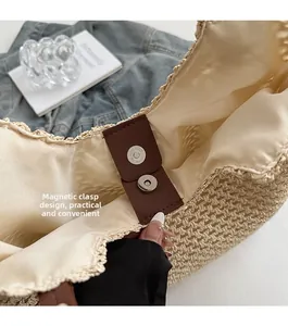 Detail of the magnetic buckle closure on a woven straw tote bag with fabric lining