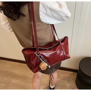 Detail of burgundy glossy faux leather tote bag with silver ring and decorative charm
