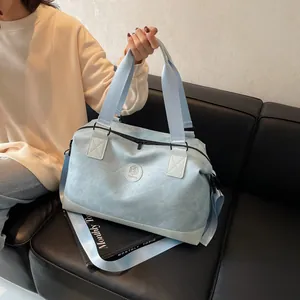 Grand sac de voyage bleu clair avec poignées et bandoulière sur canapé en cuir