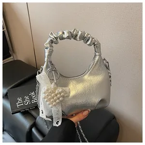 Close-up of silver pleated cloud bag with metallic finish, chain strap and pearl charm