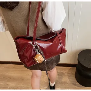 Detailed macro view of glossy burgundy leather texture and cute cat charm on the shoulder bag