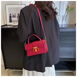 Detail der rosaroten Handtasche mit Krokodilprägung und goldenem Verschluss am Model