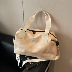 Grand sac de voyage beige marbré avec poignées blanches posé sur un banc en cuir