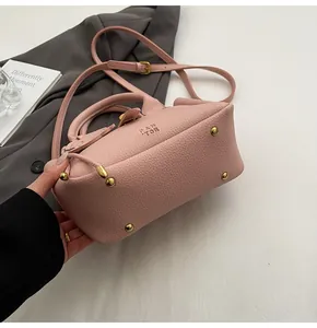 Détail du sac en cuir rose avec rivets dorés et texture grainée de litchi