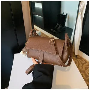 Λεπτομέρεια καφέ τσάντας χιαστί από δέρμα με λευκές ραφές και γούνινο διακοσμητικό στοιχείο