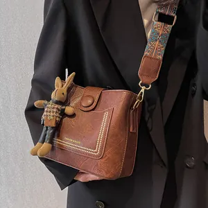 Sac seau vintage en cuir marron foncé avec bandoulière large et charm lapin mignon
