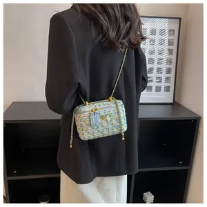 Détail du mini sac boîte en tweed avec fleur dorée et bandoulière chaîne sur un modèle