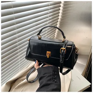 Close-up of black glossy leather handbag with vintage bronze lock and adjustable strap