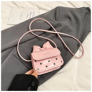 Détail du mini sac bandoulière rose à pois avec nœud 3D sur fond de blazer gris élégant