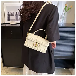 Model trägt eine cremefarbene Krokodil-Box-Handtasche mit goldener Metallschnalle