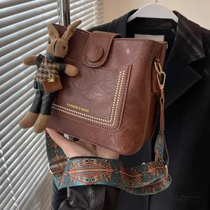 Sac seau marron rétro avec bandoulière tissée et accessoire charme lapin en peluche
