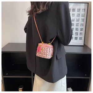 Détail d'un mini sac en tweed rose avec breloque camélia dorée et bandoulière chaîne