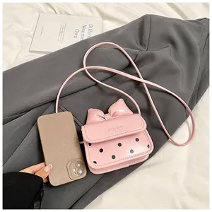 Vue détaillée du mini sac à nœud rose à côté d'un smartphone pour comparer la taille