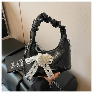 Detail of black pleated ruched bag with lace bow and heart pearl embellishment