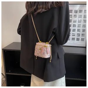 Gros plan du mini sac en tweed rose avec logo camélia doré et bandoulière chaîne