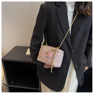 Détail du mini sac vanity en tweed rose avec camélia doré et bandoulière chaîne