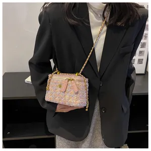 Gros plan du mini sac bandoulière en tweed rose avec chaîne dorée et détail floral