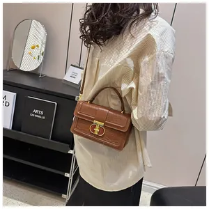 Detailansicht einer braunen Krokodilstruktur-Handtasche mit elegantem Gold-Drehverschluss