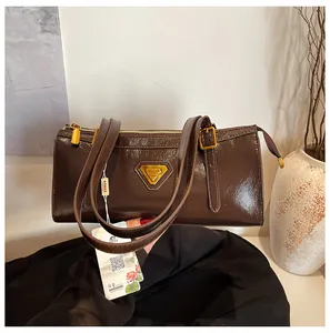 Detailaufnahme der dunkelbraunen Lackleder-Schultertasche mit goldenen Dreiecksdetails