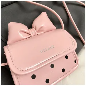 Gros plan du mini sac à bandoulière rose avec un grand nœud et des pois noirs