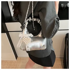 Close-up of metallic silver pleated cloud bag with lace bow and pearl heart charm