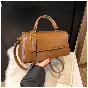 Macro detail of brown patent leather handbag with golden twist lock on plush white background