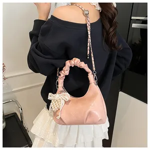 Detail of pink pleated cloud bag with lace bow and pearl charm on shiny PU leather