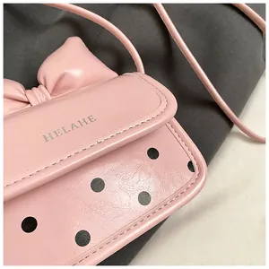 Détail du nœud rose et du motif à pois noirs sur ce mini sac à bandoulière