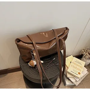 Close-up of brown oiled leather shoulder bag with creative baseball charm on a wooden stool
