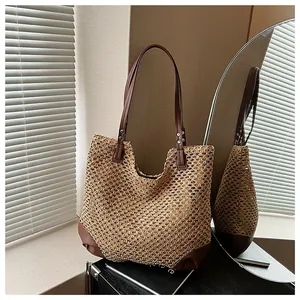 Detail of woven straw tote bag with brown leather base under artistic shutter shadows