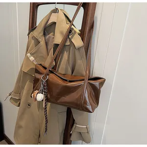 Detail of glossy brown leather tote bag with unique baseball and glove charms