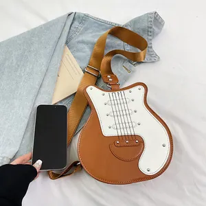 Dettaglio della borsa a tracolla creativa a forma di chitarra con borchie su tessuto bianco