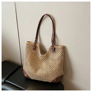 Detail of hand-woven straw tote bag with brown leather handles and silver metal rivets